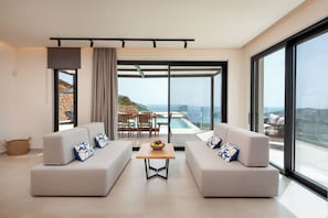 Un salon moderne avec deux canapés, une table basse et un coin repas offrant une vue sur la piscine.