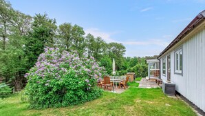 A patio with outdoor furniture, a white fence, and a house with large windows. - Beautiful home in Båstad with sauna (Båstad)