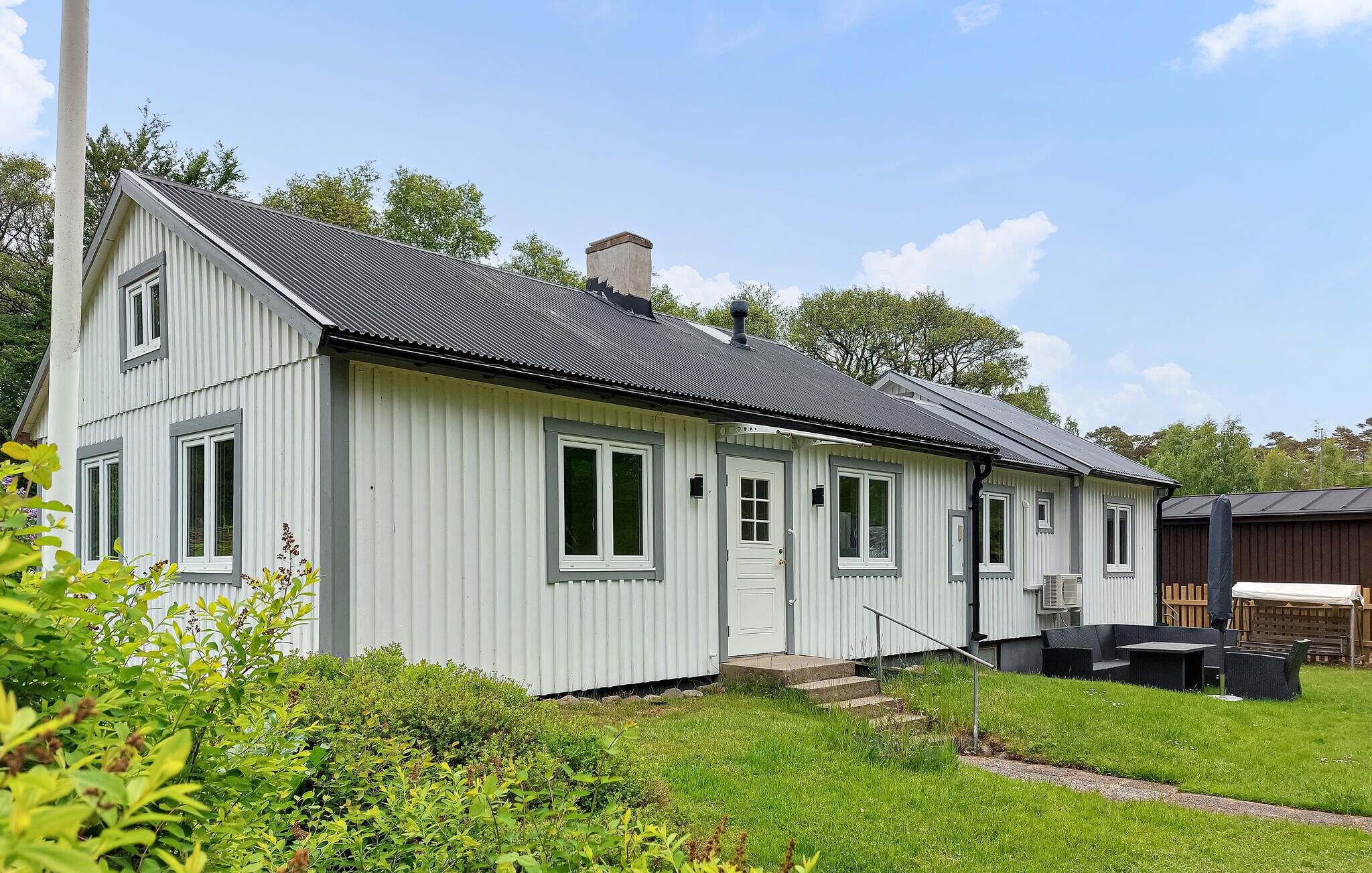 Une maison de plain-pied avec un toit à pignon, une porte d’entrée et un petit porche.