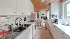A modern kitchen with white cabinets, stainless steel appliances, and a wooden ceiling. - Beautiful home in Båstad with sauna (Båstad)