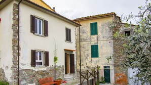A traditional building with stone walls, wooden shutters, and a bench outside.