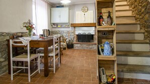 A rustic kitchen with a dining table, chairs, and a wooden staircase.
