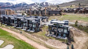 Un complexe résidentiel moderne composé de plusieurs immeubles à deux étages, dotés de grandes fenêtres et présentant une combinaison de façades en brique et en pierre.