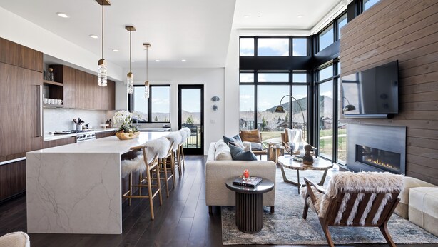 Une cuisine moderne dotée d’un îlot en marbre, de meubles en bois et de luminaires suspendus. On y trouve également un espace salon avec un canapé, une table basse et une cheminée.