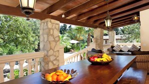 A wooden bar with fruit bowls, a stone pillar, and a balcony with outdoor furniture. - Beautifully Restored Country House, A/C Private Pool, Mountain Views - 10mins to Old Town Pollenca (Pollença)