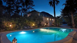 A swimming pool with lounge chairs and a lantern, surrounded by trees and a house in the background. - Beautifully Restored Country House, A/C Private Pool, Mountain Views - 10mins to Old Town Pollenca (Pollença)