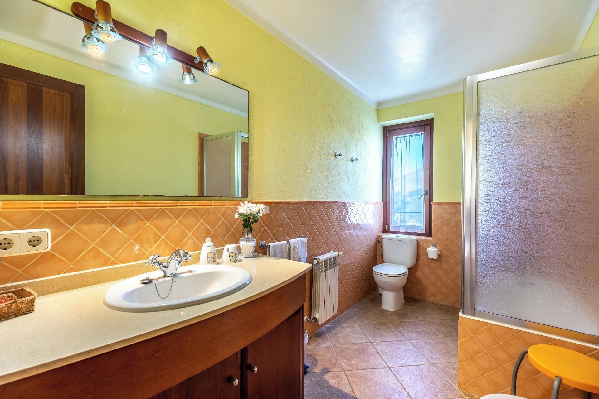 Un baño con dos lavamanos, un espejo, un inodoro, un radiador y una ventana.
