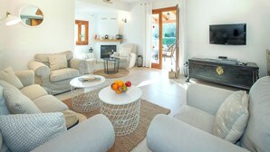 Un saló modern amb una llar de foc, una televisió i una zona de menjador amb vista a l'exterior.