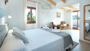 Un dormitori amb un llit gran, una cadira, una taula i una finestra amb cortines.