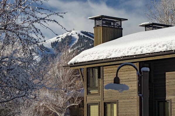A building with a snow-covered roof and a wooden facade, set against a backdrop of a snow-covered mountain.