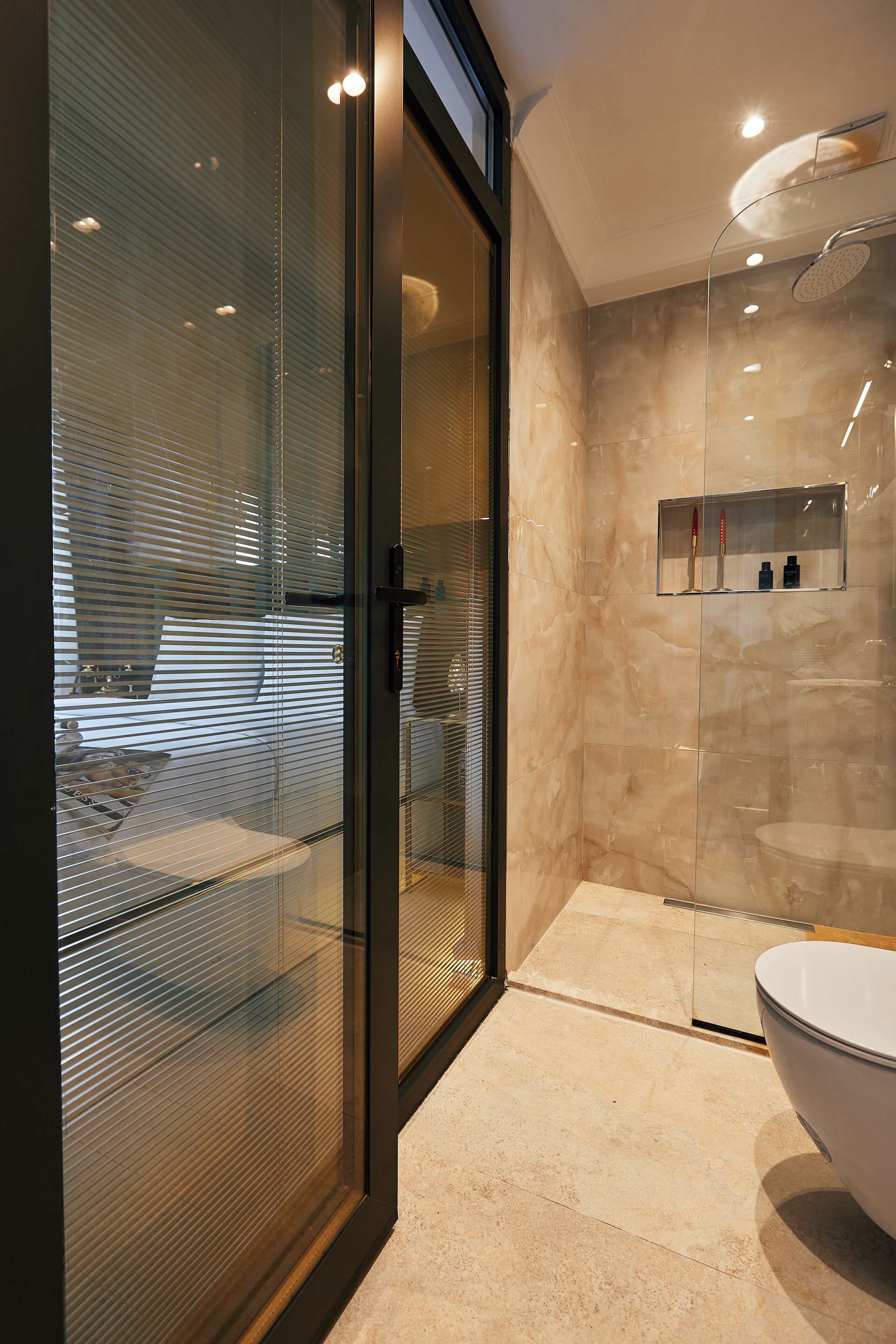 Ein modernes Badezimmer mit Duschkabine aus Glas, einer weißen Badewanne und einer Marmorwand.