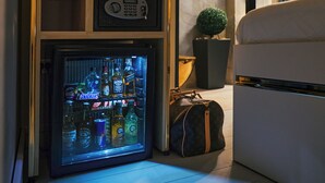 Ett kompakt vardagsrum med en minibar, bokhyllor, en krukväxt och en soffa.
