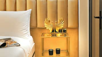 A modern hotel room with a large bed, a bedside table with a decorative lamp, and a glass partition wall.