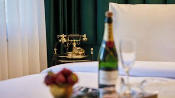 A bed with a tray of fruits, a bottle of champagne, and a glass.