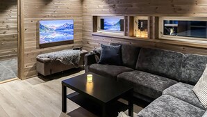 A cozy living room with a sofa, a coffee table, and a TV mounted on the wall. - Cozy home in ålen with WiFi (Ålen)