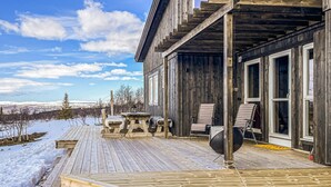 A wooden cabin with a deck, outdoor seating, and a view of snow-covered mountains. - Cozy home in ålen with WiFi (Ålen)