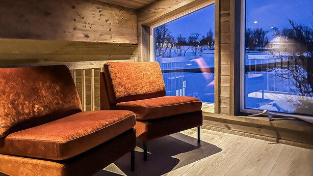 A cozy cabin interior with two plush armchairs, a wooden ceiling, and a large window overlooking a snowy landscape. - Cozy home in ålen with WiFi (Ålen)