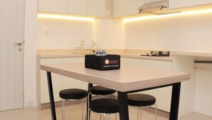 Une cuisine moderne avec un plan de travail de couleur claire, un plateau noir contenant des bouteilles et une cuisinière encastrée.