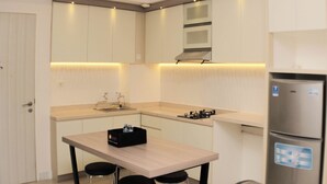 Une cuisine moderne avec des meubles blancs, un réfrigérateur en acier inoxydable et un coin bar avec des tabourets.
