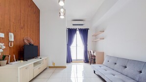 A modern living room with a sofa, TV, wooden cabinet, and a large window with curtains. - Nice And Comfort 2Br Apartment At 30Th Floor M-Town Residence (Gading Serpong)