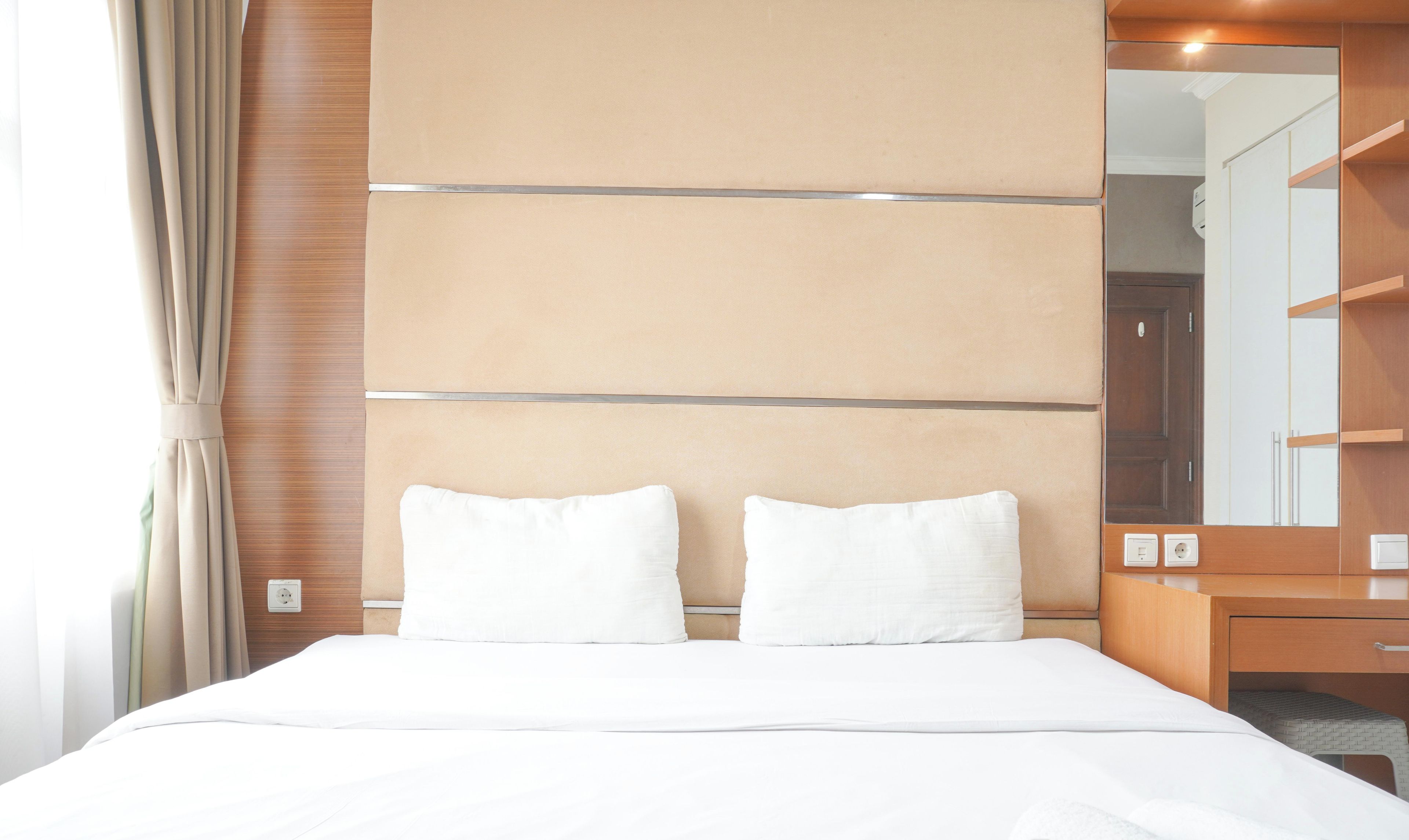 A hotel room with a large bed, a wooden headboard, a mirror, and a wooden wardrobe.