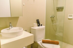 Une salle de bain équipée d’un lavabo, de toilettes et d’une douche à parois de verre.