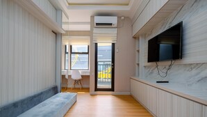 Ein modernes Interieur mit einem an der Wand montierten Flachbildfernseher, einer Couch und einem kleinen Tisch mit Lampe.