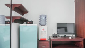 A hotel room with a minibar, a water dispenser, a television, and a desk. - Compact Studio At Margonda Residence 1 Apartment (Depok)