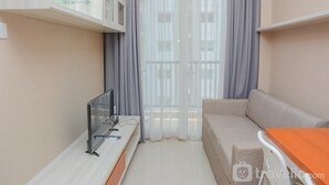 A modern living room with a sofa, a TV, and a wooden table. - Comfortable 1Br At Signature Park Grande Near Cawang Station Apartment (Jakarta)