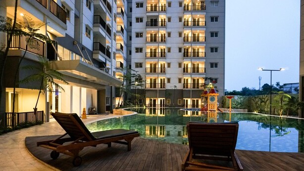 A hotel pool area with lounge chairs, a children's play structure, and a reflection pool. - Comfortable 1Br At Signature Park Grande Near Cawang Station Apartment (Jakarta)