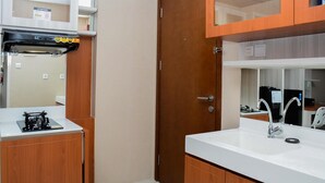 A compact kitchen with a gas stove, a sink, and wooden cabinets. - Comfortable 1Br At Signature Park Grande Near Cawang Station Apartment (Jakarta)