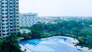 Un edificio alto con el letrero 'BPK PENABUR' y una piscina que ofrece vistas a una zona residencial.