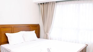 Una cama bien hecha con sábanas blancas en una habitación de hotel.