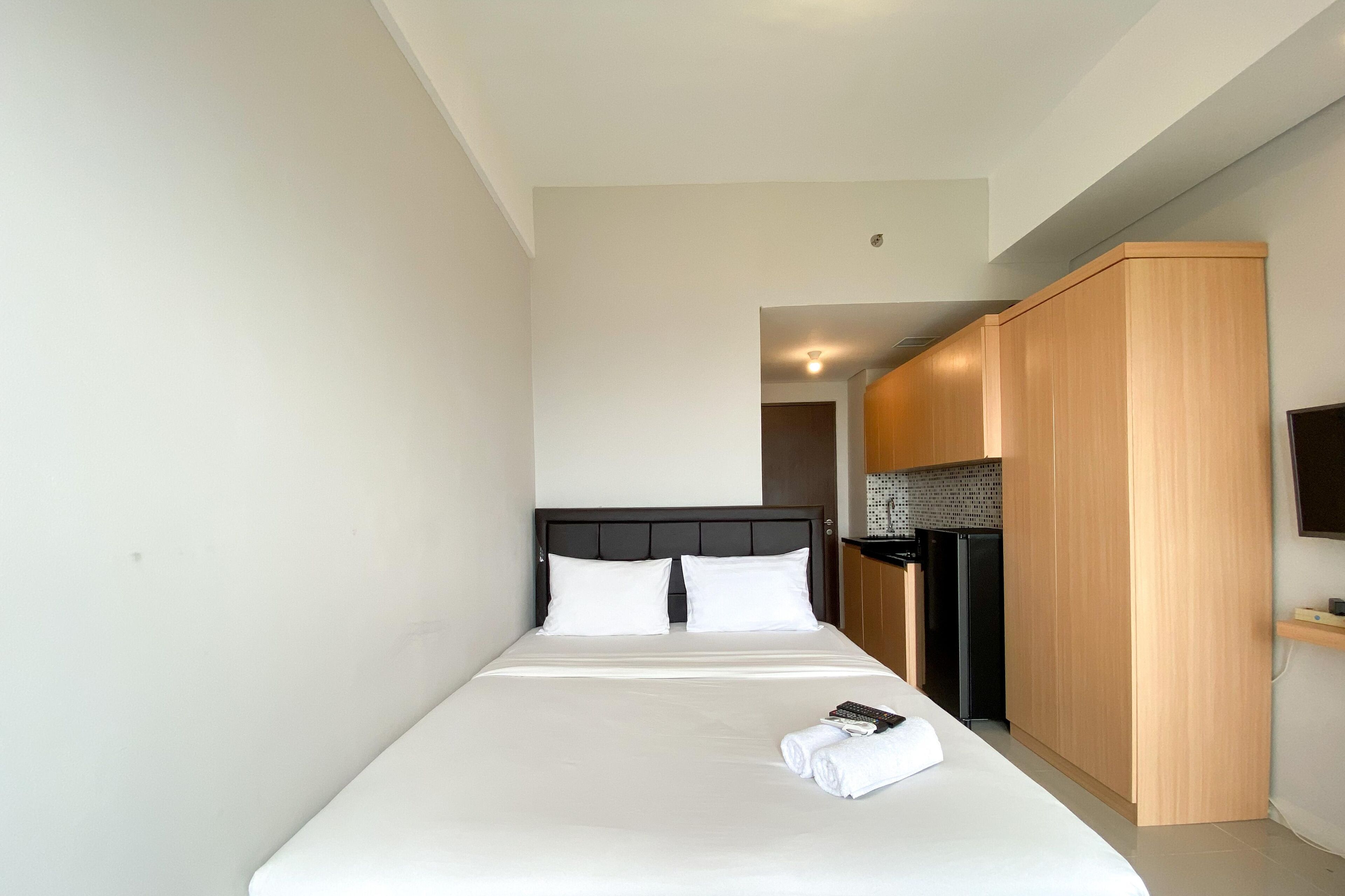Une chambre d’hôtel avec un lit simple, une armoire en bois et un coin cuisine.