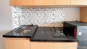 Una cocina compacta con encimera negra, pileta de acero inoxidable y cocina a gas.