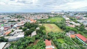 Vista aérea de un paisaje urbano con una combinación de edificios residenciales y comerciales, un amplio espacio verde abierto y un edificio destacado en la lejanía.