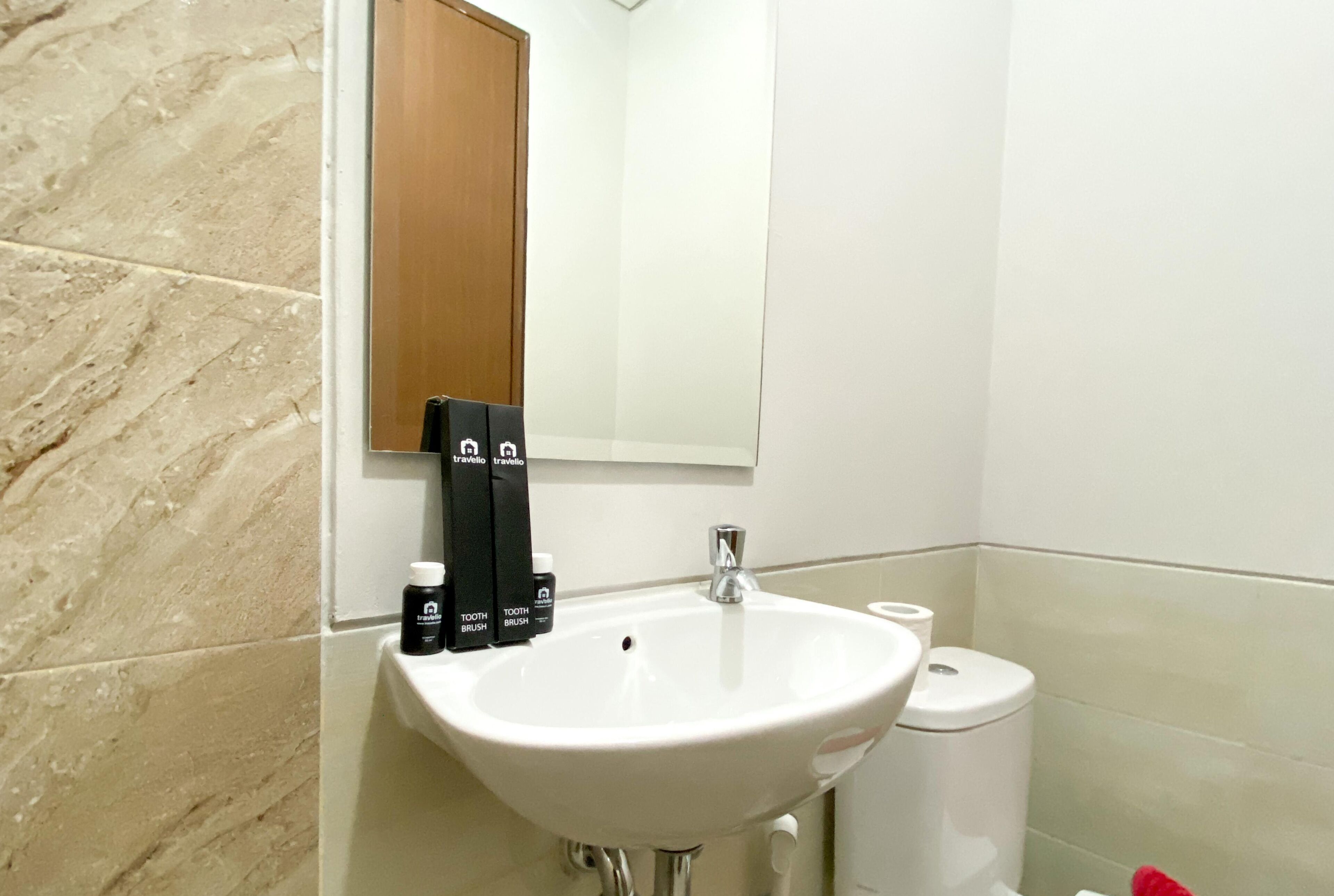 A bathroom with a white sink, a mirror, and toiletries on the wall.