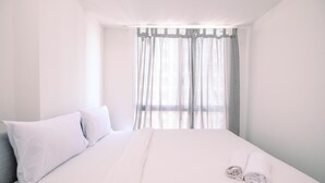 A hotel room with a large bed, white bedding, and sheer curtains. - Comfort And Nice 2Br At Tokyo Riverside Pik 2 Apartment (Teluknaga)