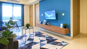 Una sala de estar moderna con un televisor de pantalla plana montado en una pared azul, una mesa consola de madera y una alfombra con estampado geométrico.