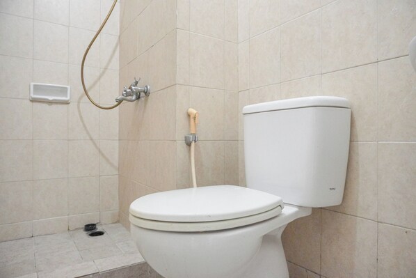 Inodoro blanco con bidé de madera en un baño con baldosas color crema.