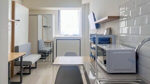 A compact kitchen with a sink, a microwave, and a window providing natural light. - Nice And Homey Studio (No Kitchen) At Bandaraya - Tallasa City Makassar Apartment (Makassar)