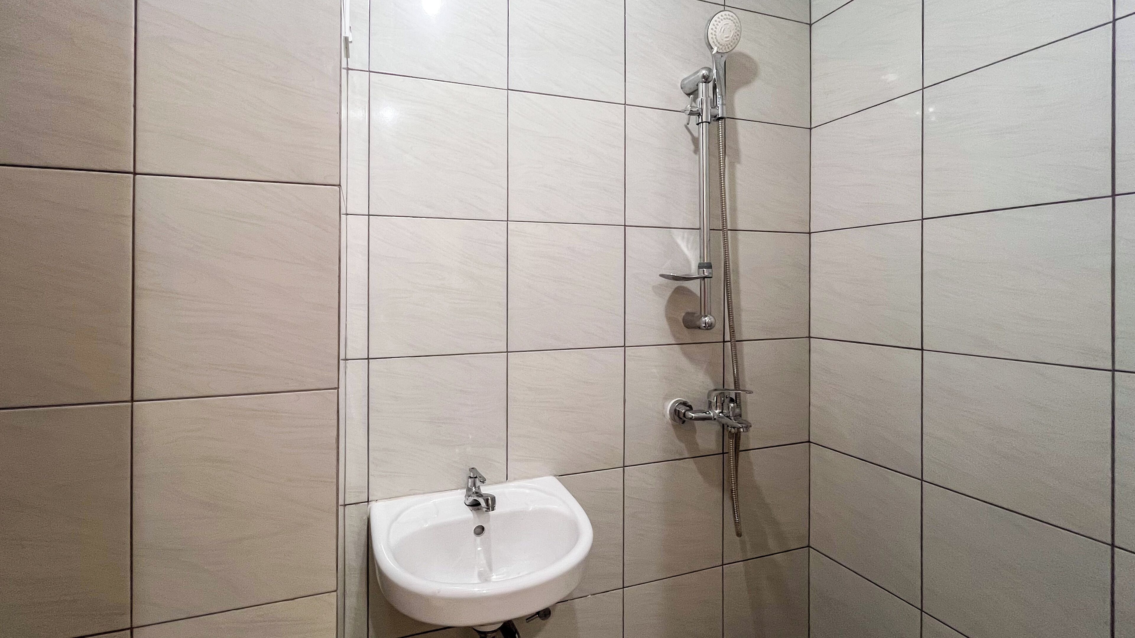 A bathroom with a shower, a sink, and tiled walls.