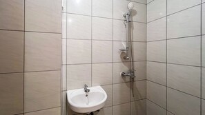 A bathroom with a shower, a sink, and tiled walls. - Nice And Homey Studio (No Kitchen) At Bandaraya - Tallasa City Makassar Apartment (Makassar)
