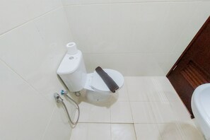 A compact bathroom with a toilet, showerhead, and separate shower area.