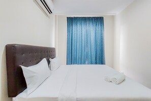 Relax in a cozy retreat with a neatly made bed and comfortable seating area.