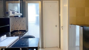 A compact kitchen with a refrigerator, stove, and a window with blinds.