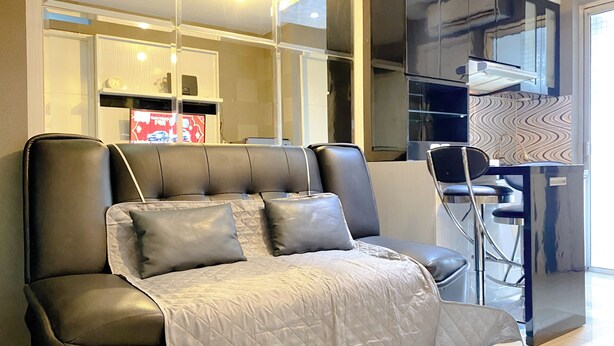 A modern living room with a sofa, a dining area with a chair, and a kitchen area with a microwave.