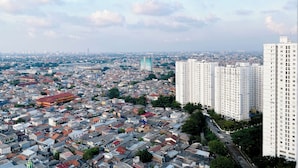 A cityscape with densely packed buildings, including high-rise residential structures and a prominent green skyscraper.