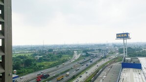 Eine Autobahn mit mehreren Fahrspuren und Fahrzeugen, darunter Lastwagen und Autos. Ein großes, blaues Schild mit dem IKEA-Logo ist sichtbar.
