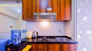 Una cocina compacta con armarios de madera, estufa integrada y pileta de acero inoxidable.